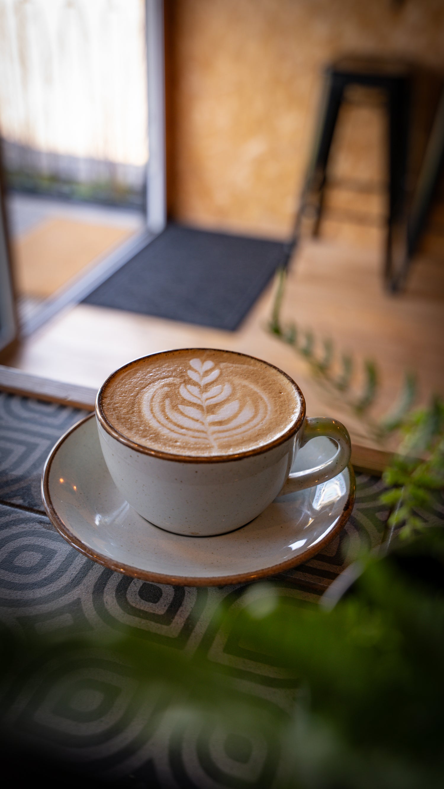Cappuccino with latte art on a saucer in a cozy indoor setting